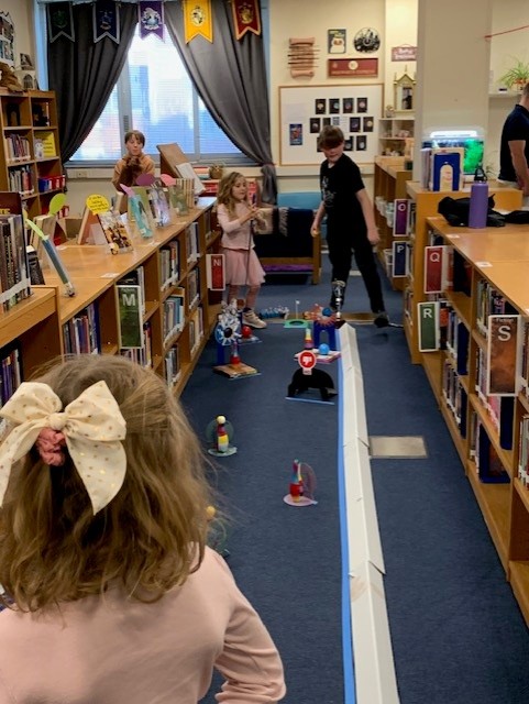 Students playing putt putt golf in the library during Literacy & Math Family Night