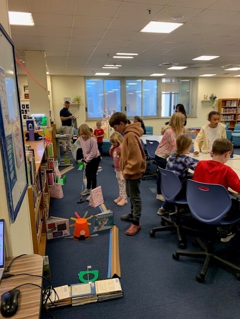 Students playing putt putt golf in the library during Literacy & Math Family Night